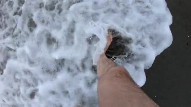 Poilu jambes masculines marcher sur le sable de la mer plage à travers la vague de mousse POV — Video