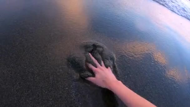 Рука касается мокрого песка на пляже — стоковое видео