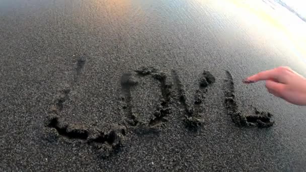 Mão feminina desenhar amor inscrição no oceano areia POV — Vídeo de Stock