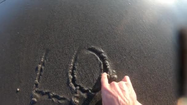 Meereswelle im Licht der Sonne spült Inschrift Love POV weg — Stockvideo