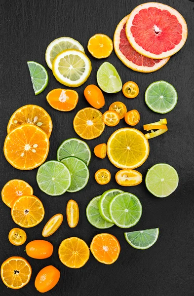 Pamplemousse, orange, mandarine, citron, citron vert et kumquat sur fond noir — Photo