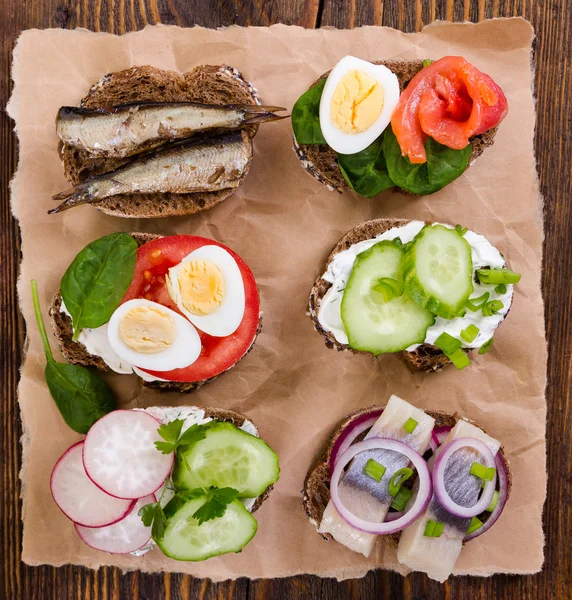 Small sandwiches on wooden background. Top view. — Stock Photo, Image