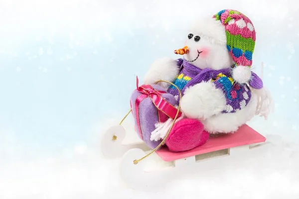 Снеговик на санках с рождественским подарком — стоковое фото