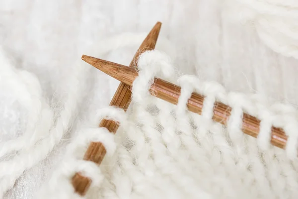 Образец вязания из шерстяной пряжи белого цвета на деревянном трикотаже — стоковое фото
