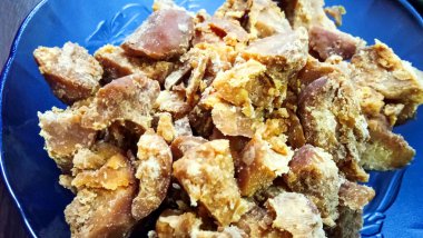 Bir kase Jaggery 'nin yakın çekimi. Baston suyunun yoğunlaştırılmış bir ürünüdür. Genellikle hurma ağaçları veya pekmez kristalleri ayrılmadan palmiye özsuyunun rengi altın kahverengiden koyu kahverengiye değişebilir.