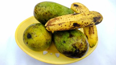 Beyaz arka planda üç olgun mango ve muz.