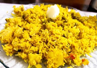 Basmati pilavı, bezelye, patates, domates ve hafif baharatlarla yapılmış taze pişmiş Hint sebze pulaosunun yakın çekimi.