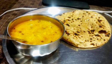Dal (mercimek körisi) içeren geleneksel Hint yemeği paslanmaz çelik bir tabakta Roti (yassı ekmek) ile çelik bir kasede servis edilir.