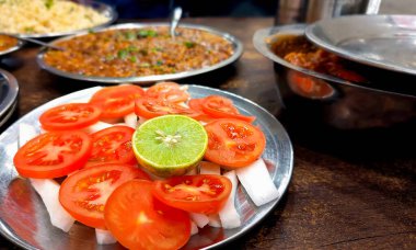 Çelik tabaklarda servis edilen Hint yemeği, jeera pilavı, rajma köri, paneer köri ve taze domates, turp ve limon salatası içerir.