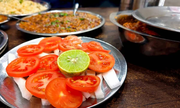 Çelik tabaklarda servis edilen Hint yemeği, jeera pilavı, rajma köri, paneer köri ve taze domates, turp ve limon salatası içerir.