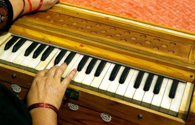 Bir insanın eli harmonyum çalarken, tuşları ve ahşap tasarımı vurgularken yakın plan görüntüsü.