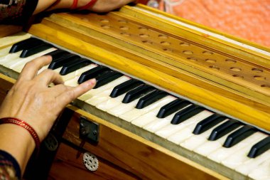 Bir insanın eli harmonyum çalarken, tuşları ve ahşap tasarımı vurgularken yakın plan görüntüsü.