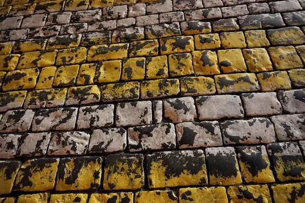大きな石畳の暗い舗装。塗装黄色と白色. — ストック写真