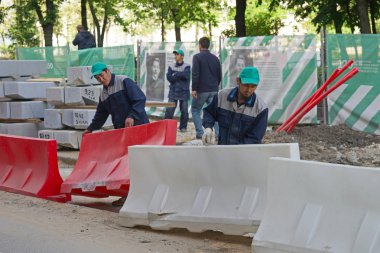 Moscow, Rusya Federasyonu - 15 Mayıs 2016: Asya işçiler bir yol eskrim yükleyin. Yolun şehir Güzelleştirme programı Moskova'da My sokak içinde yeniden inşası.