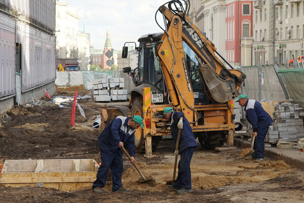 МОСКВА, РОССИЯ - 15 мая 2016 года: Строительная техника и рабочие с лопатами. Реконструкция проезжей части в рамках программы благоустройства города "Моя улица" в Москве
.