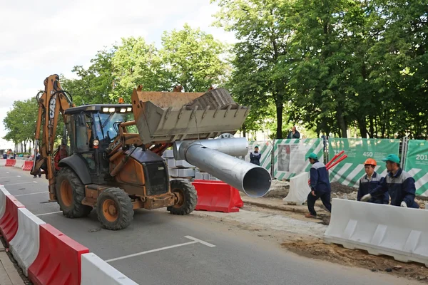 Moskou, Rusland - 15 mei 2016: Bulldozer een metalen pijp uitvoering. Wederopbouw van de rijbaan binnen de stad verfraaiing program mijn straat in Moskou. — Stockfoto