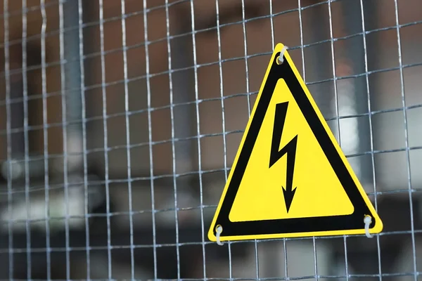 Metal mesh ve sarı elektrik tehlike işareti.