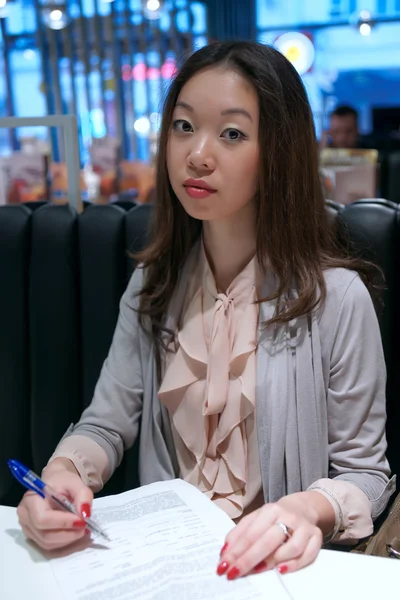 Asian girl writing on a sheet — Stock Photo, Image