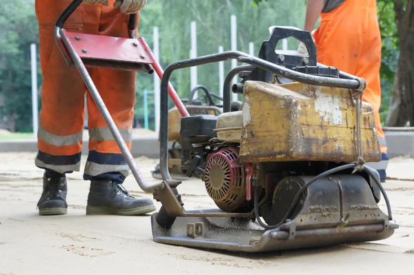 Plate compactor prepares sandy surface. — Stock Photo, Image