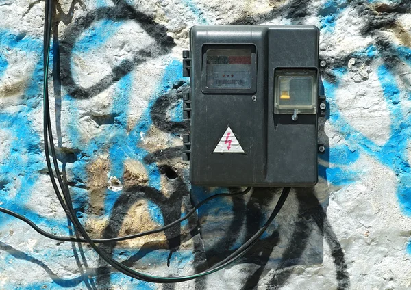Old electric meter with wires on the painted stone wall. — Stock Photo, Image