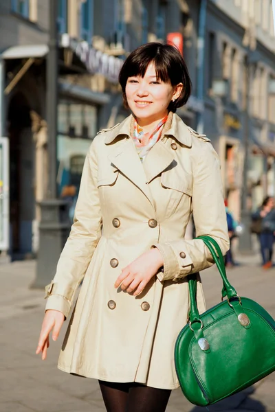 Улыбающаяся темноволосая девушка с зеленой сумкой . — стоковое фото
