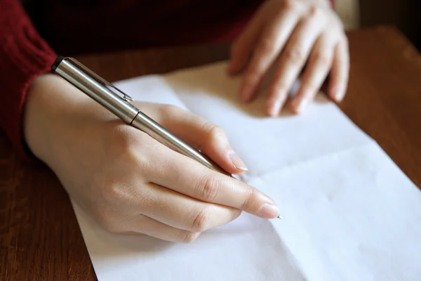 Menselijke hand met een balpen en een leeg vel papier. — Stockfoto