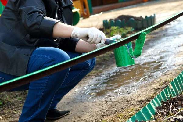 La mujer pinta la cerca de pintura verde . — Foto de Stock