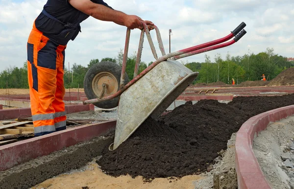 Arbetaren häller smutsa från skottkärran. — Stockfoto