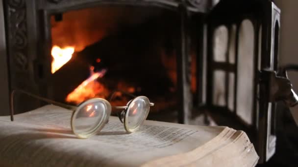 Brýle, otevřená kniha a krb — Stock video