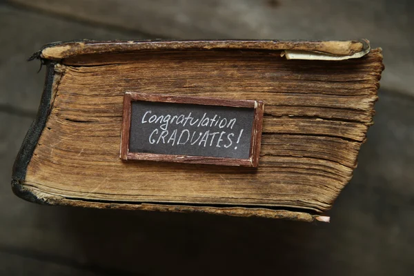 Felicitaciones graduados texto y libro vintage en la mesa — Foto de Stock