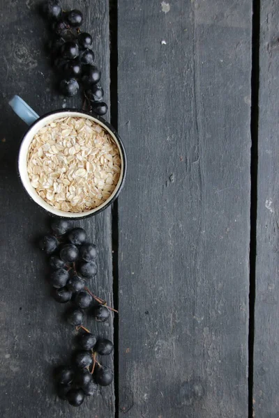 Fundo de comida, aveia em uma caneca e uvas em uma velha mesa vintage — Fotografia de Stock