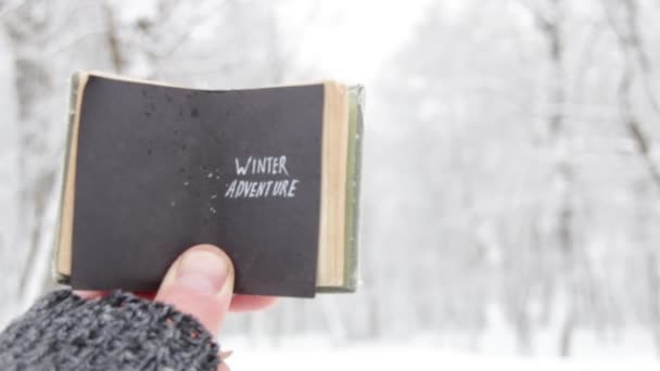 Aventura invernal. El viajero sostiene un libro con texto. — Vídeo de stock