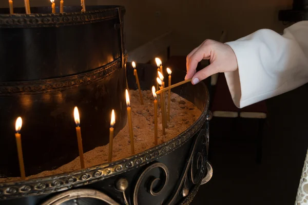 La mujer enciende velas en una iglesia — Foto de Stock