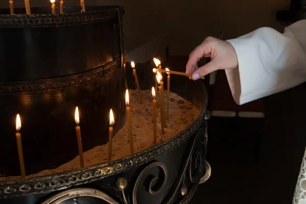 La mujer enciende velas en una iglesia — Foto de Stock