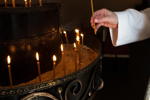Frau zündet Kerzen in einer Kirche an — Stockfoto