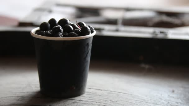 Black chokeberry in a paper cup on the table — Stock Video