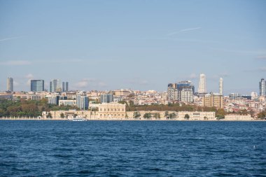 Dolmabahe Palace on the Bosphorus: Grand Imperial Structure and Gardens Set Against the Modern Skyscraper Skyline of Istanbul's European Side on a Bright, Sunny Day in Trkiye.
