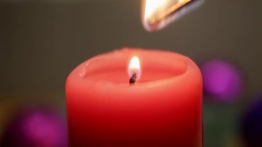 Bir adam kırmızı bir Noel mumu yakar ve bir kibrit yakar. Noel toplarıyla, yakın plan..