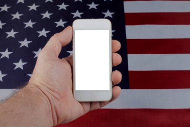ABD bayrağının arka planında bir adamın elinde cep telefonu, seçici odaklanma 