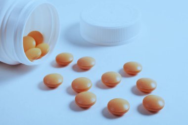 Beyaz arkaplanda haplardaki vitaminler, yakın plan, tonlu mavi