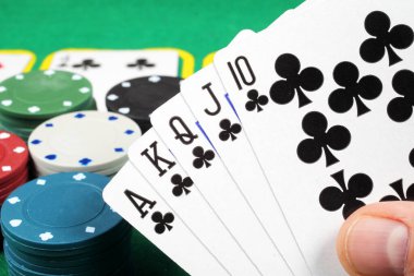 Poker fişleri ve kartlar masada, royal floş kombinasyonu kazanıyor. Seçici odak, yakın plan.