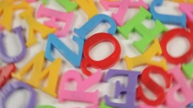Beyaz arkaplan üzerinde İngiliz alfabesinin çok renkli plastik harfleri beyaz arkaplan üzerinde döner 