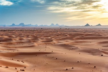 Erg Admer 'in Sahra Çölü, Cezayir' deki manzarası. Gün doğumunda kum tepeleri dalgaları ve Tassilis 'in kaya oluşumları.