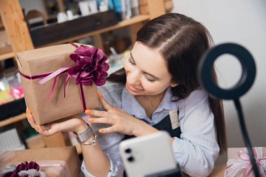 Giysi kutusu ambalajı, genç kadın zanaatkar sanat alanında internet video dersini telefonda kaydetti.