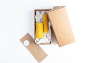 Beyaz arka planda hediye olarak el işi paketlerinde bal mumundan yapılmış sarı mumlar.