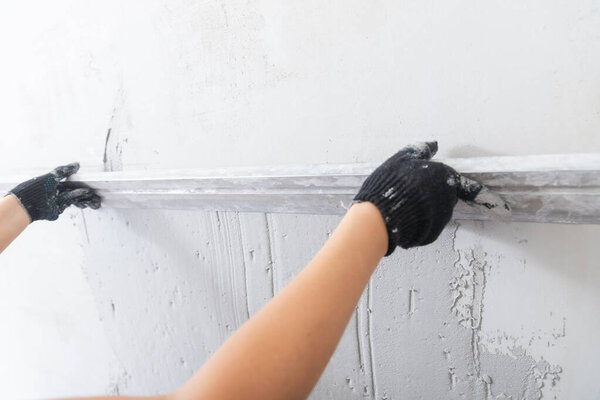 Plastering concrete walls, builder levels gray surface