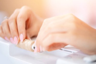 Genç terzi elbisesi tasarımcısı dikiş makinesine iplik sapını yerleştirdi