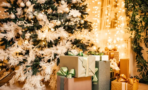Δώρα κουτιά βρίσκονται κάτω από το χριστουγεννιάτικο δέντρο στο εσωτερικό, bokeh φωτίζεται στο παρασκήνιο — Φωτογραφία Αρχείου
