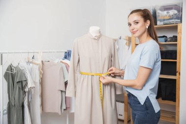 Terzi, mankenle çalışan genç bir kız elbise için terzi iğnesi takıyor. Elbise dikmek için işyeri