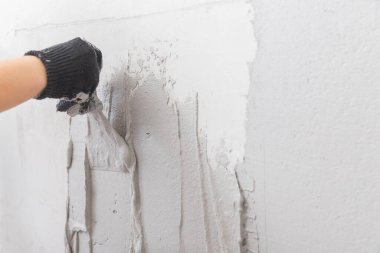 İnşaat işçisi yüzey seviyesine beton duvara malayla sıva uyguluyor